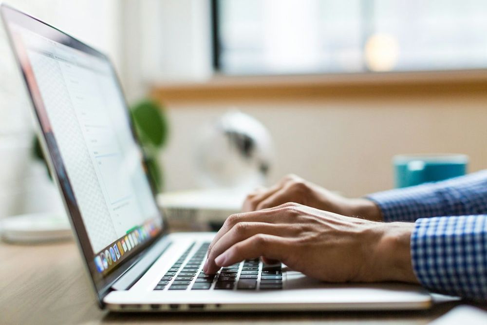 Accountant working on a laptop with printed reports